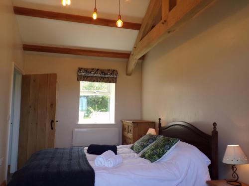 1 dormitorio con 1 cama con sábanas blancas y ventana en Detached barn with valley views near Cardigan, en Cardigan