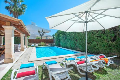 a swimming pool with chairs and an umbrella at Owl Booking Villa Llenaire Gran - 3 min Walk to the Beach in Port de Pollensa