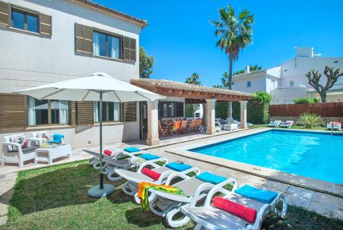 a pool with chairs and an umbrella next to a house at Owl Booking Villa Llenaire Gran - 3 min Walk to the Beach in Port de Pollensa