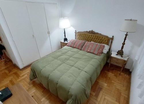 a bedroom with a bed with a green comforter at San Benito 1538 by depptö in Buenos Aires