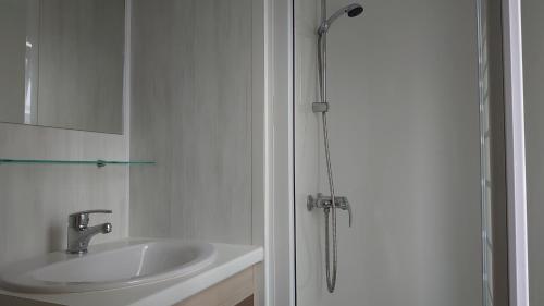 a white bathroom with a sink and a shower at Chalet 156 voor 6 personen De Kuilart 5-sterren camping in Friesland in Koudum