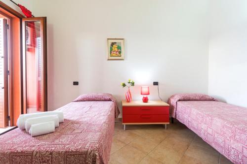a bedroom with two beds and a table with a dresser at Residence La Corte Di Anastasia in Torpè