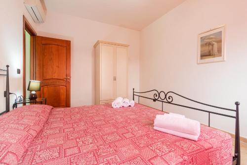 a bedroom with a pink bed with two towels on it at Residence La Corte Di Anastasia in Torpè