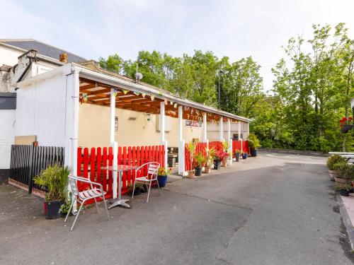 a building with red and white chairs in a parking lot at OYO Old Oak Tree Inn in Hounslow