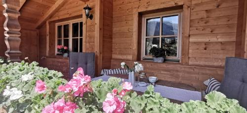 een houten huis met een tafel, stoelen en bloemen bij Alpbach Loft in Alpbach