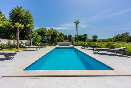 a swimming pool with two chairs and a table at Villa Palma with Heated Private Pool in Podhum