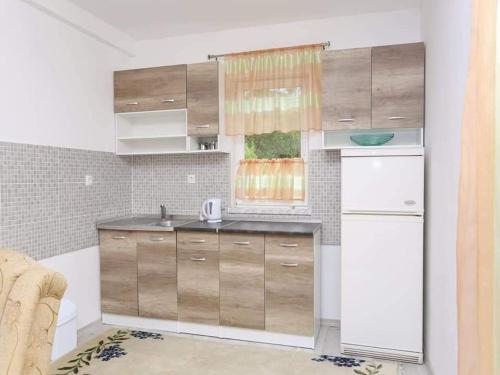 a kitchen with wooden cabinets and a white refrigerator at Apartman Maida in Blagaj