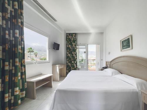 a hotel room with a large bed and a large window at Apartamentos La Carabela in Puerto de la Cruz