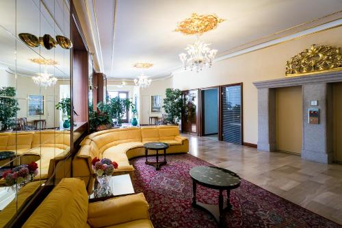 a lobby with yellow couches and tables in a building at Hotel Milan Speranza Au Lac in Stresa