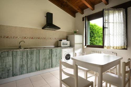 uma cozinha com uma mesa, um lavatório e uma máquina de lavar louça em Apartamento con piscina cerca de Llanes PDRA001R em Lledías