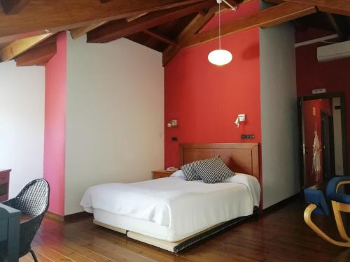 a bedroom with a white bed and a red wall at Casa Buda Conors & Spa in Foz