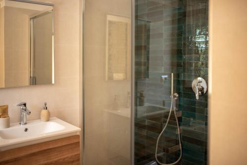 una ducha con una puerta de cristal junto a un lavabo en Agriturismo La Genziana en Alguer