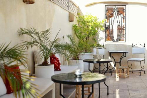 una habitación con mesas, macetas y sillas en Riad Dollar Des Sables & Spa, en Marrakech