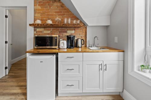 a kitchen with white cabinets and a brick wall at ENTIRE 1 BEDROOM APARTMENT ACROSS FROM GOOGLE - br5 in Kitchener