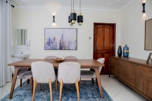a dining room with a wooden table and chairs at Lux Suites Eldoret Luxury Villas in Eldoret