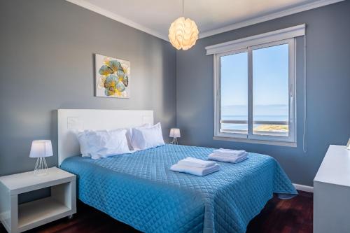 ein Schlafzimmer mit einem blauen Bett und einem Fenster in der Unterkunft Caniço Vip Lodging by Madeira Sun Travel in Santa Cruz
