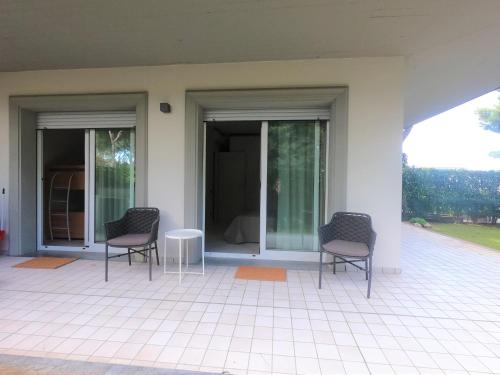 a porch with three chairs and a table and windows at Michelangelo rta in Cinquale
