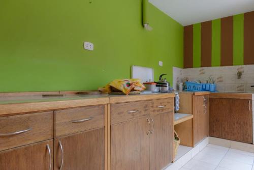 a kitchen with green walls and wooden cabinets at la casa de la guajira in Cusco
