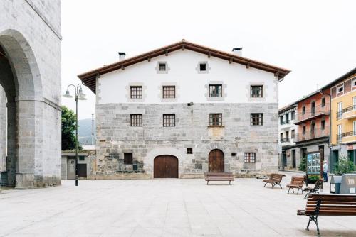 an old stone building with benches in a courtyard at Arangiz Etxea in Aulestia