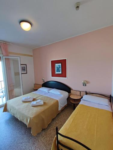 a hotel room with two beds and a window at Hotel Primavera sul mare in Lido di Savio