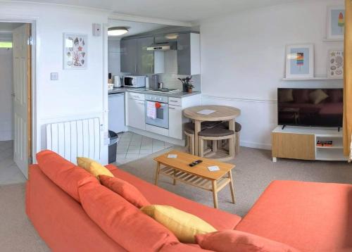 a living room with an orange couch and a kitchen at Parkdean Sea Valley chalet Westward Ho! & Bideford in Bideford