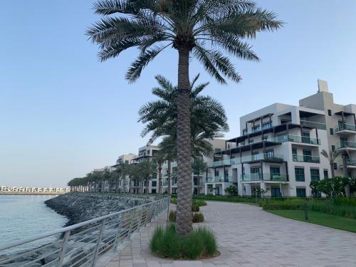 a palm tree in front of a building next to the water at Apartments with three bedrooms at address hotel in Sharm