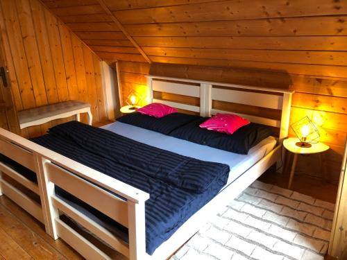 a bed in a wooden cabin with two pink pillows at Čičmanský ľudový dom in Čičmany