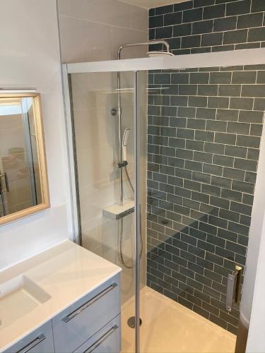une salle de bain avec une douche en verre avec un lavabo dans l'établissement GITE Maison Nomah Maison haut standing proche plages, classé 5*, à Plouha