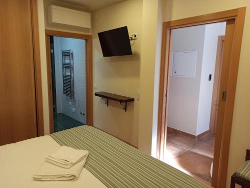 a bedroom with a bed and a television on the wall at Fontanário House in Alpiarça