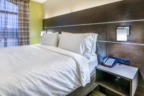 a bed in a hotel room with a phone on a table at Holiday Inn Express & Suites Longview North by IHG in Longview