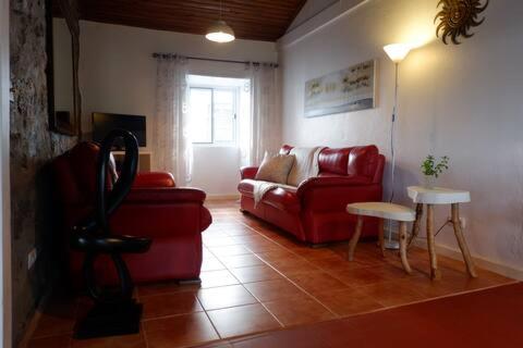 a living room with a red couch and a table at Coastal Trail Cottage in São Vicente Ferreira