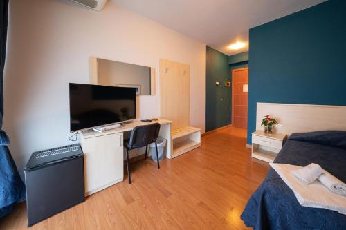 a room with a bed and a desk with a flat screen tv at Hotel Break House Ristorante in Terranuova Bracciolini