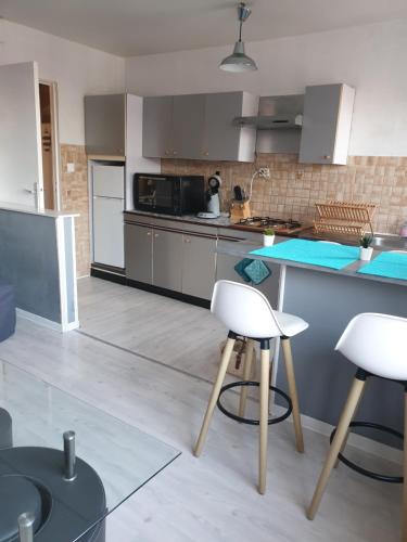 une cuisine avec des chaises blanches et un comptoir bleu dans l'établissement appartement malo les bains plage, à Dunkerque