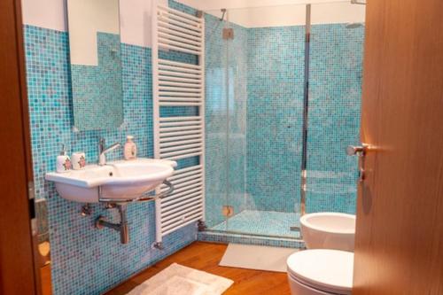 uma casa de banho em azulejos azuis com um lavatório e um chuveiro em B&B Borgo Margherita em Udine