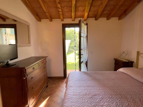 a bedroom with a bed and a dresser with a television at Casa Sophia con piscina - ingresso, giardino, barbecue e parcheggio privati by ToscanaTour in Guardistallo
