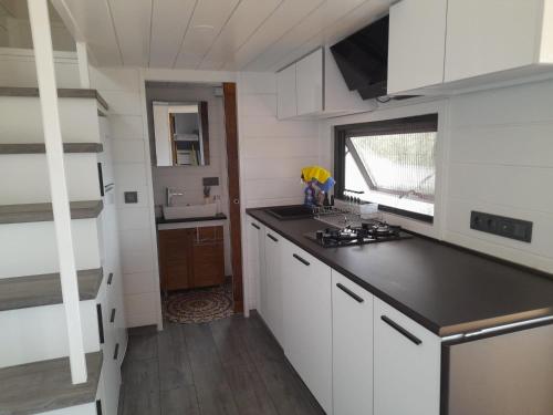 a kitchen with white cabinets and a black counter top at Lovin Göcek Tiny House Butterfly in Gökçeovacık