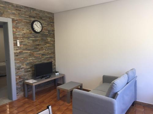 a living room with a couch and a clock on a brick wall at Apartamento Armães in Viana do Castelo