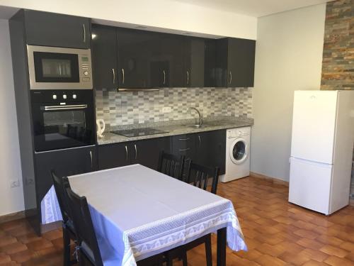 a kitchen with a table and a white refrigerator at Apartamento Armães in Viana do Castelo