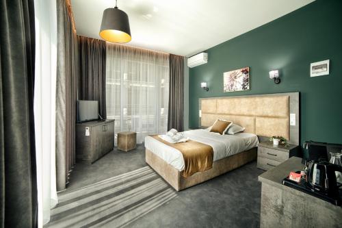 a bedroom with a large bed and green walls at Hotel Nordic Twins & Wellness in Rădăuţi