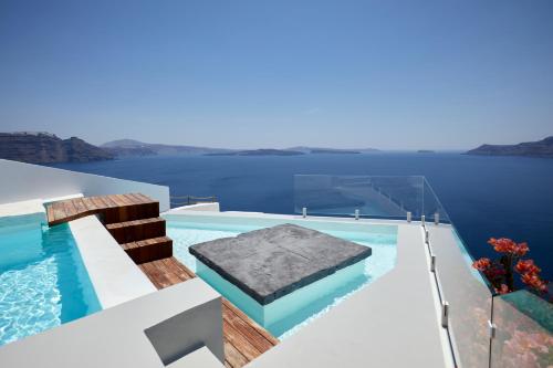 a swimming pool on the side of a house on the water at The Saint Hotel in Oia