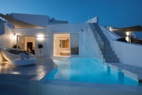 a villa with a swimming pool at night at The Saint Hotel in Oia