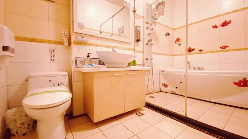 a bathroom with a toilet and a sink and a tub at Hai Yang Feng Qing Homestay in Hualien City