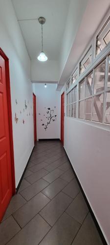 an empty hallway with red doors and birds on the wall at Cayalito Apart Hotel in Guatemala