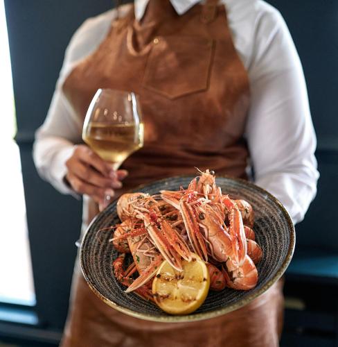 a person holding a plate of shrimp and a glass of wine at Loch Fyne Hotel & Spa in Inveraray