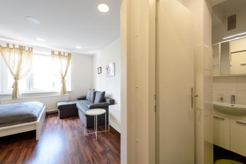 ein Wohnzimmer mit einem Sofa, einem Bett und einem Waschbecken in der Unterkunft Vienna Lights Apartments - Hernals in Wien
