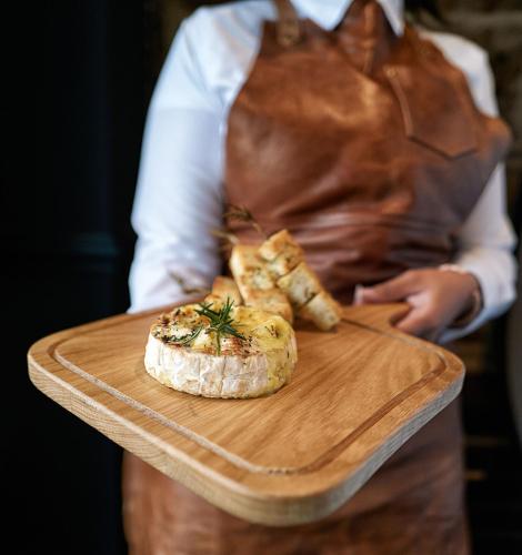 a person holding a cutting board with a plate of food at Loch Fyne Hotel & Spa in Inveraray