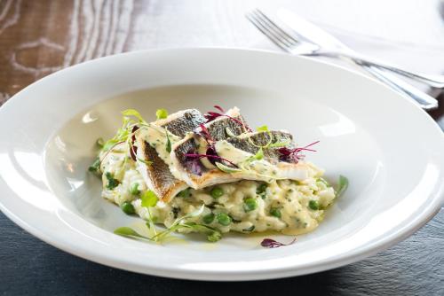 a white plate of food with fish on risotto at Loch Fyne Hotel & Spa in Inveraray