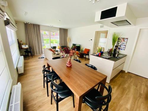 uma sala de jantar e sala de estar com mesa e cadeiras em Luxury apartment "Volmolen" with garden, terrace and free parking em Harelbeke