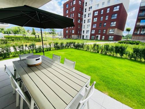 a wooden table with an umbrella and a lawn at Modern luxurious suite in new private apartment building by the river in Harelbeke