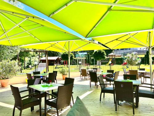a restaurant with tables and chairs and yellow umbrellas at Aparthotel Kastel Seiser Alm in Castelrotto